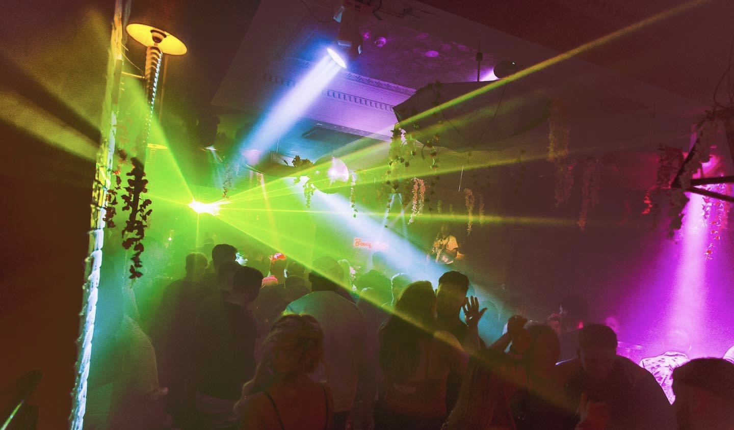 Colourful nightclub lighting and laser effects operating over a busy dancefloor